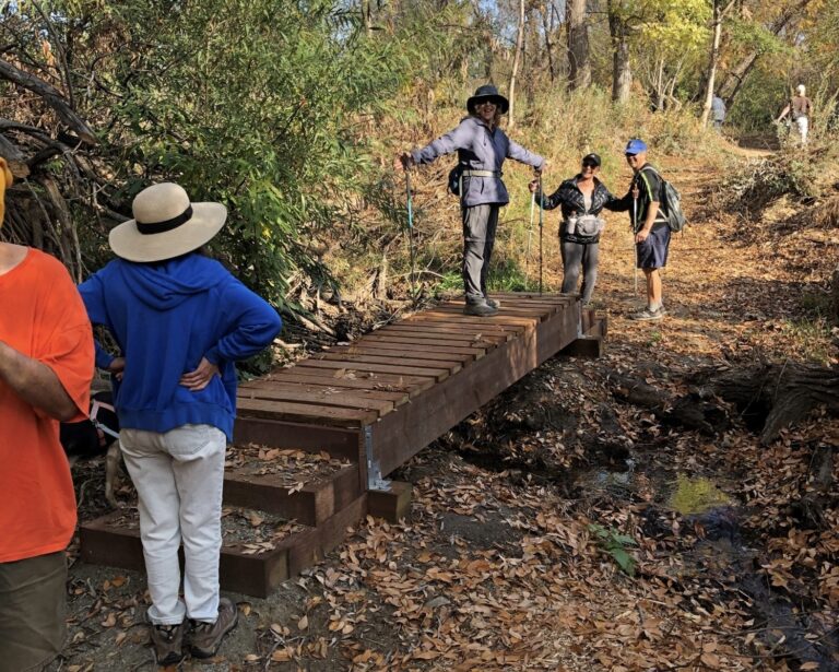 woman standing on foot bridge with hiking group