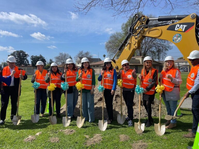 8 people in hard hats holding shovels for a groundbreak ceremony